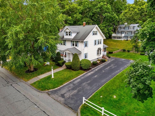 view of front of property with aphalt driveway, a chimney, a front yard, and fence