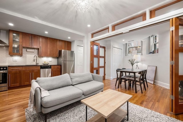 living room featuring light wood finished floors, baseboards, a notable chandelier, and recessed lighting