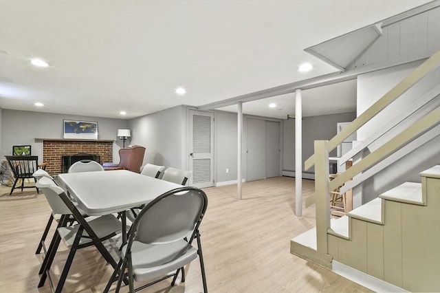 dining area with light wood-type flooring, recessed lighting, stairway, a brick fireplace, and baseboards