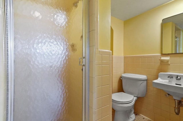 full bath featuring a shower stall, wainscoting, tile patterned flooring, toilet, and tile walls