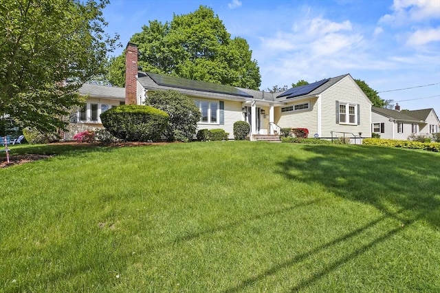 single story home featuring solar panels, a chimney, and a front lawn