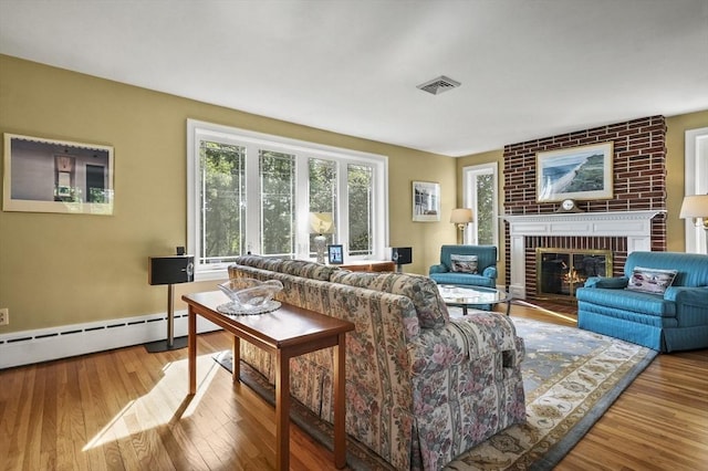 living room with baseboard heating, a fireplace, wood finished floors, and baseboards