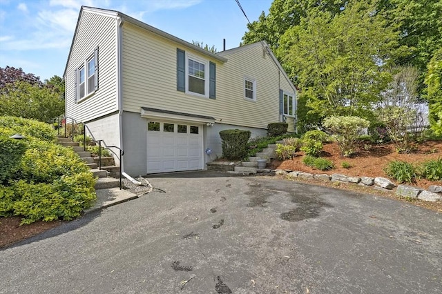 view of front of house featuring stairway, an attached garage, and driveway