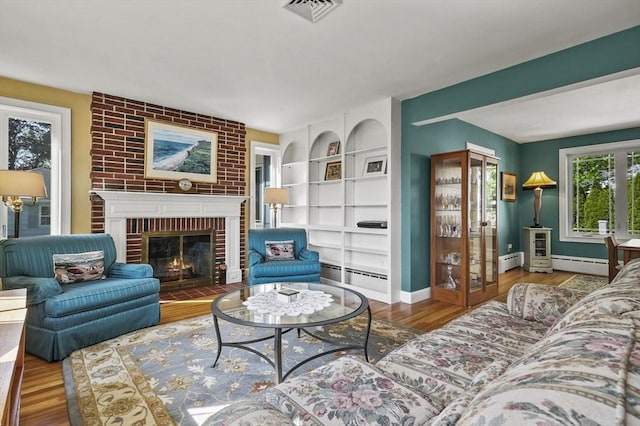 living room featuring a baseboard heating unit, wood finished floors, and baseboards