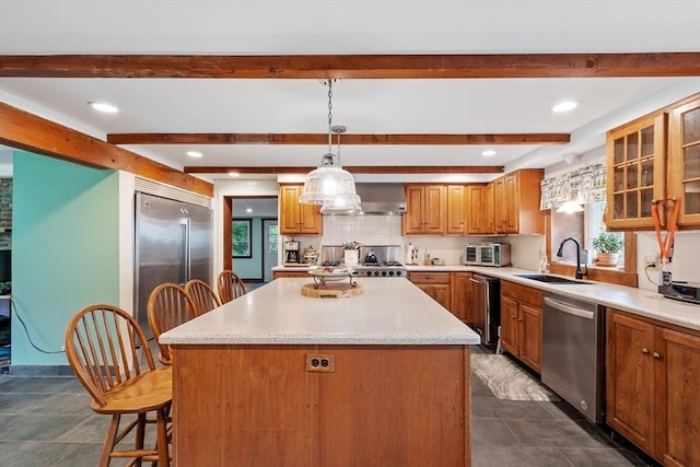 kitchen with a kitchen island, stainless steel appliances, hanging light fixtures, and sink