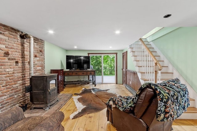 living room with light wood-type flooring, brick wall, and a wood stove