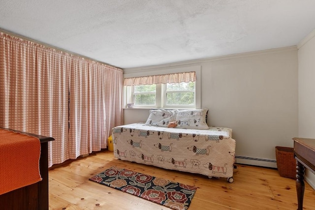 bedroom featuring baseboard heating, crown molding, and light hardwood / wood-style floors