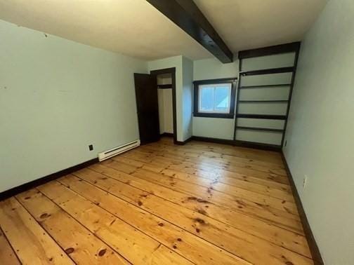 interior space with light wood-type flooring, baseboard heating, and beamed ceiling