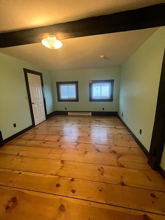 empty room with beam ceiling, light hardwood / wood-style flooring, and a baseboard radiator