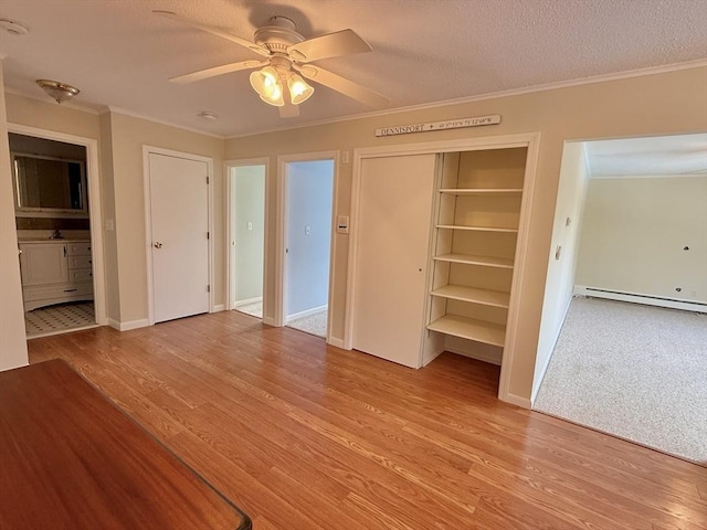 174 Upper County Unit 2-15, Dennis, MA 02639 - unfurnished bedroom featuring baseboard heating, wood finished floors, ornamental molding, a closet, and a textured ceiling