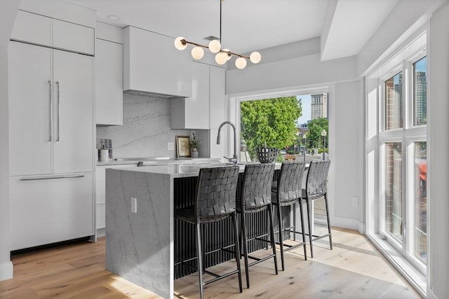 43 Stillman St Unit 201, Boston, MA 02113 - kitchen featuring modern cabinets, a kitchen bar, white cabinetry, paneled built in refrigerator, and light wood-style flooring