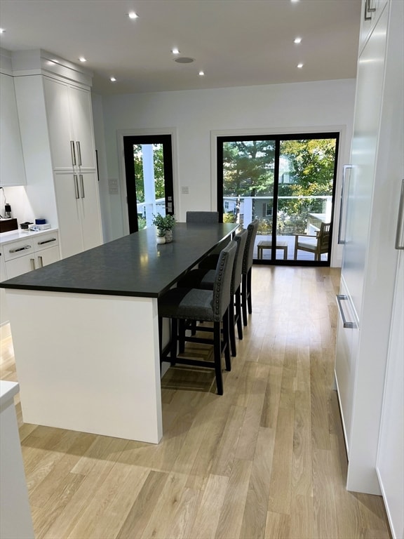 kitchen featuring light wood-type flooring, a kitchen island, white cabinetry, and plenty of natural light