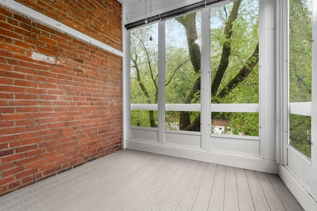 unfurnished sunroom with wood finished floors and brick wall