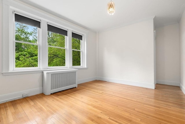 unfurnished room featuring baseboards, radiator, crown molding, and light wood-type flooring
