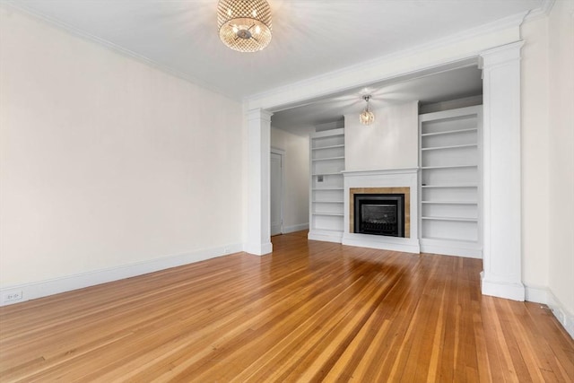 unfurnished living room with baseboards, light wood finished floors, a fireplace, and crown molding