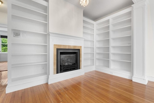 unfurnished living room with hardwood / wood-style flooring, a tile fireplace, and built in features