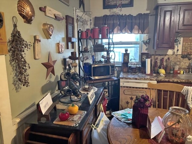 kitchen featuring tasteful backsplash, dark countertops, stainless steel microwave, and a sink