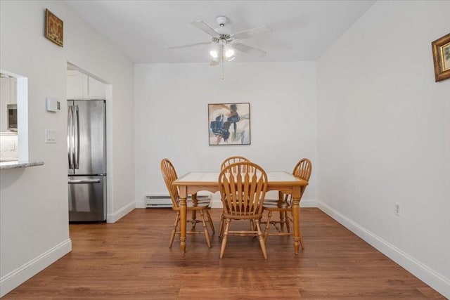 dining area featuring a ceiling fan, baseboards, baseboard heating, and wood finished floors