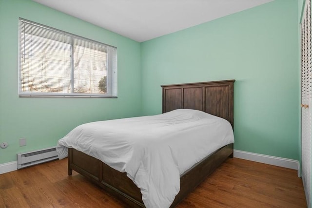 bedroom with a baseboard radiator, baseboards, and wood finished floors