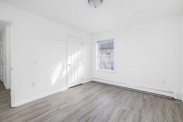 38 Brook St Unit 1, Central Falls, RI 02863 - unfurnished bedroom with a baseboard heating unit and wood finished floors