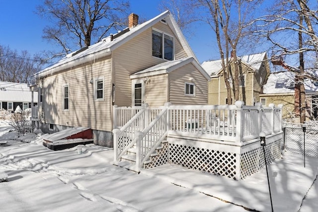 snow covered back of property with a deck