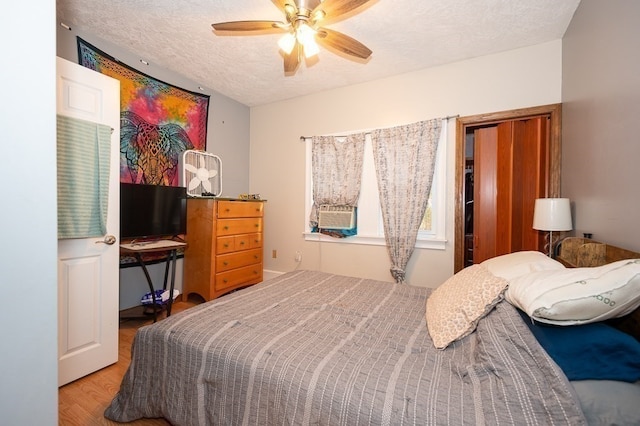 bedroom with ceiling fan, light hardwood / wood-style flooring, and a textured ceiling