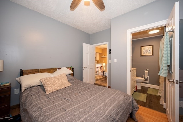 bedroom with ceiling fan, ensuite bathroom, hardwood / wood-style floors, and a textured ceiling