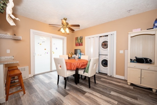 dining area featuring ceiling fan, a textured ceiling, dark hardwood / wood-style floors, and stacked washer / drying machine