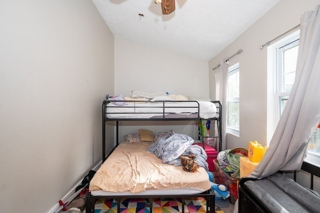 bedroom featuring ceiling fan, vaulted ceiling, and a textured ceiling