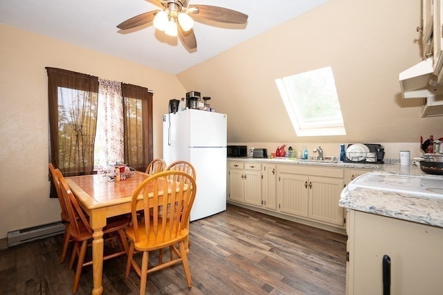 dining space featuring ceiling fan, lofted ceiling with skylight, hardwood / wood-style flooring, and sink