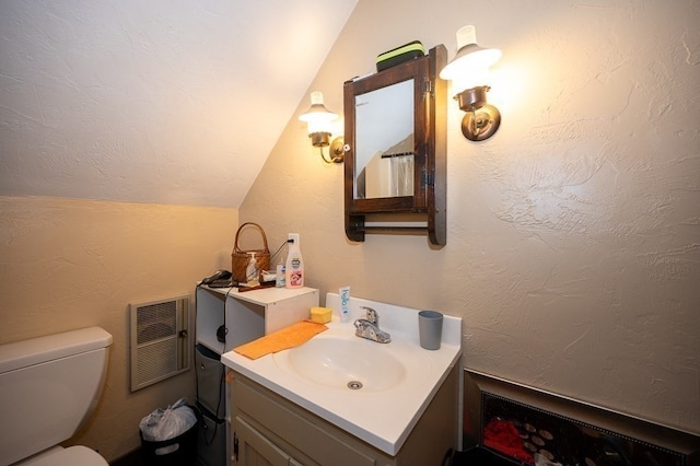 bathroom featuring vaulted ceiling, vanity, and toilet