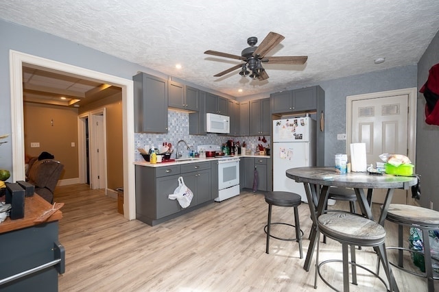 kitchen with ceiling fan, white appliances, a textured ceiling, gray cabinets, and light wood-type flooring