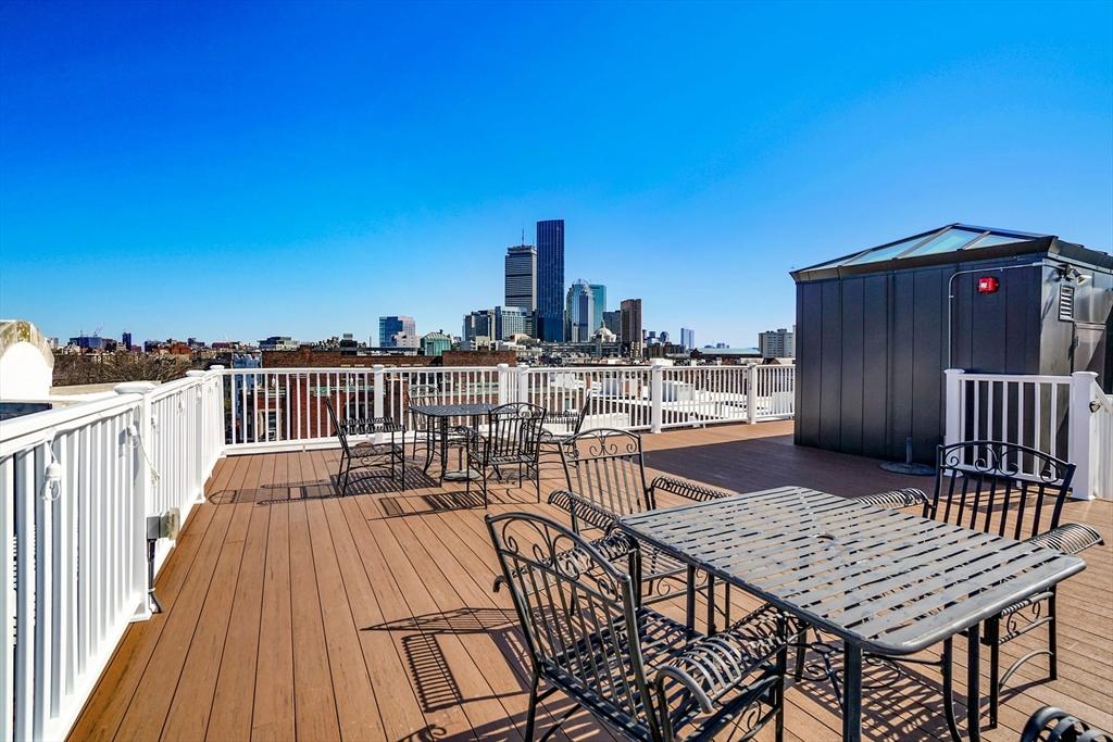 wooden terrace featuring outdoor dining area and a skyline view