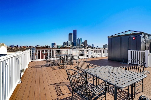 wooden terrace featuring outdoor dining area and a skyline view