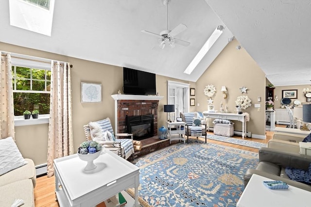 39 High Beacon Way, Marshfield, MA 02050 - living area featuring a skylight, ceiling fan, vaulted ceiling, light wood-style flooring, and a brick fireplace