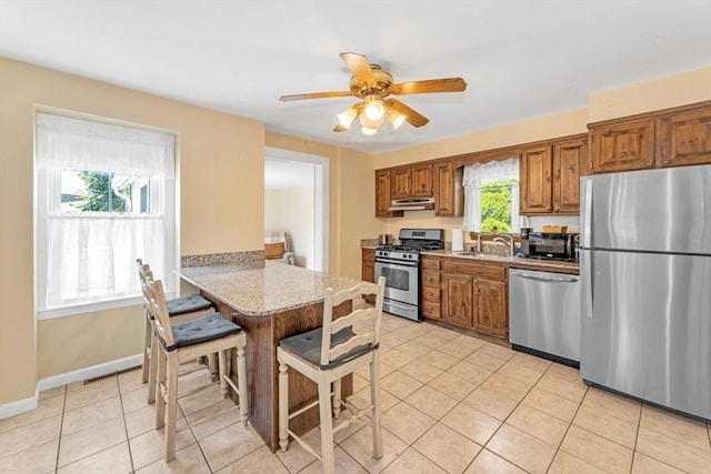 252 Railroad Ave, Norwood, MA 02062 - kitchen featuring appliances with stainless steel finishes, light tile patterned floors, brown cabinets, and a ceiling fan