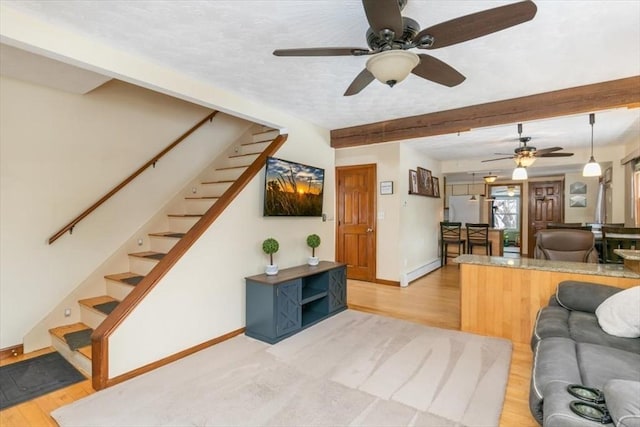 living room featuring ceiling fan, light hardwood / wood-style floors, and beamed ceiling