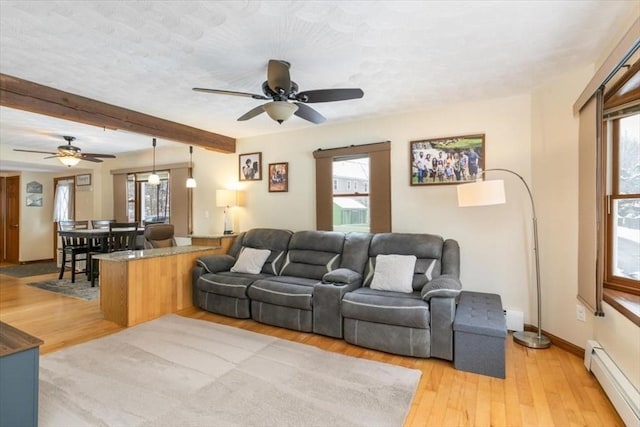 living room featuring plenty of natural light, light hardwood / wood-style flooring, and a baseboard heating unit