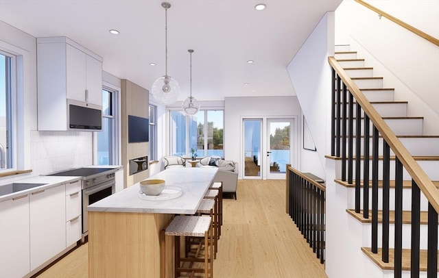 kitchen featuring a sink, white cabinets, light wood-style floors, modern cabinets, and backsplash