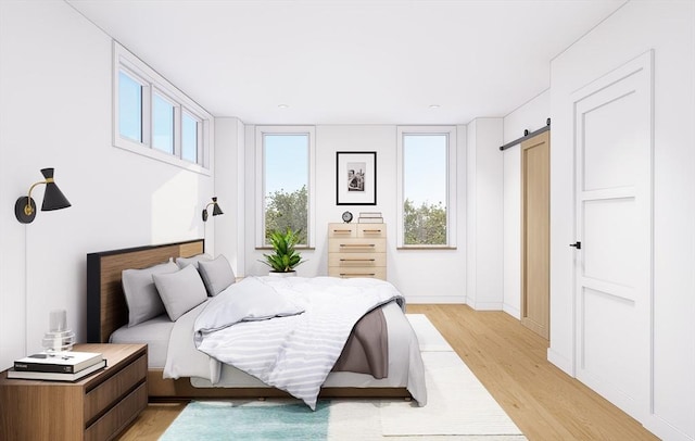 bedroom featuring baseboards, light wood-type flooring, and a barn door