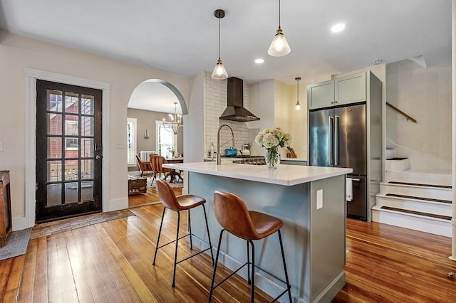 2 Oxford Pl, Worcester, MA 01609 - kitchen with wall chimney exhaust hood, high end fridge, light countertops, wood-type flooring, and arched walkways