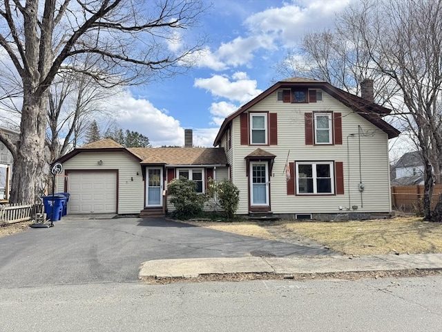 view of front of house with entry steps, an attached garage, driveway, and a chimney