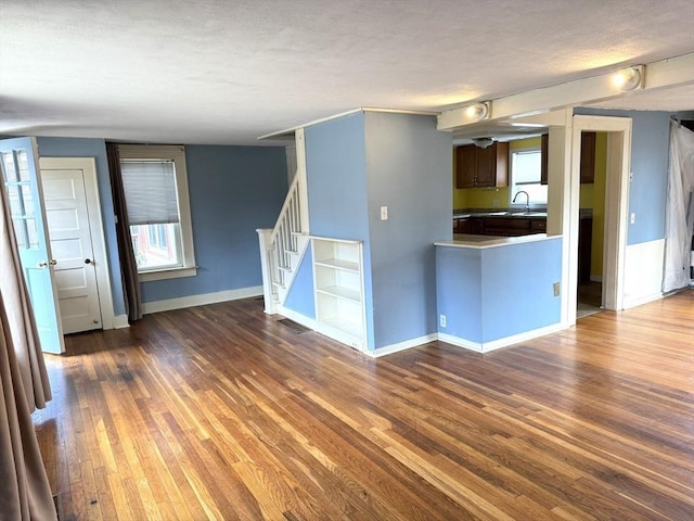 interior space with a sink, baseboards, a textured ceiling, and dark wood-style floors