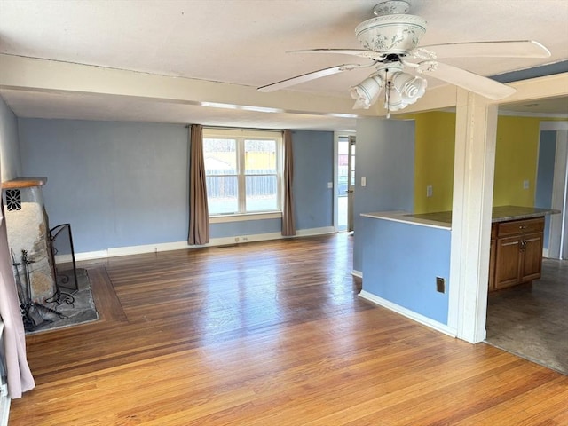 unfurnished living room featuring light wood-style floors, baseboards, and a ceiling fan