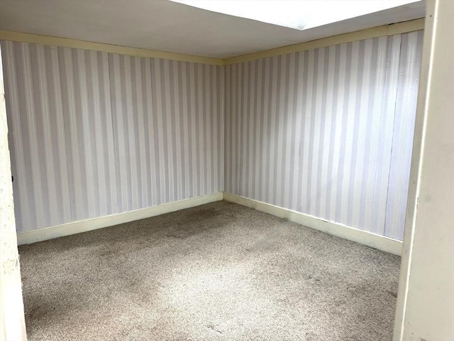 carpeted empty room featuring baseboards and wallpapered walls