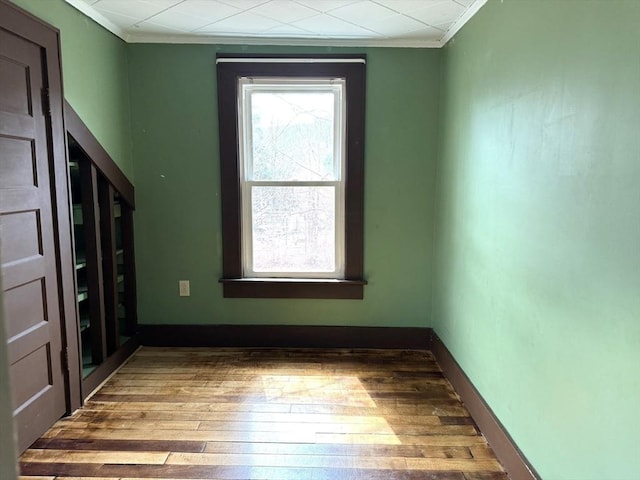 spare room with baseboards, hardwood / wood-style floors, and ornamental molding