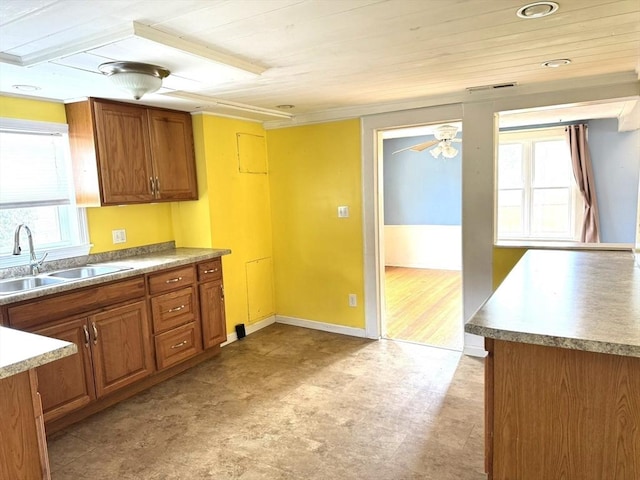 kitchen with a sink, visible vents, brown cabinetry, and ceiling fan