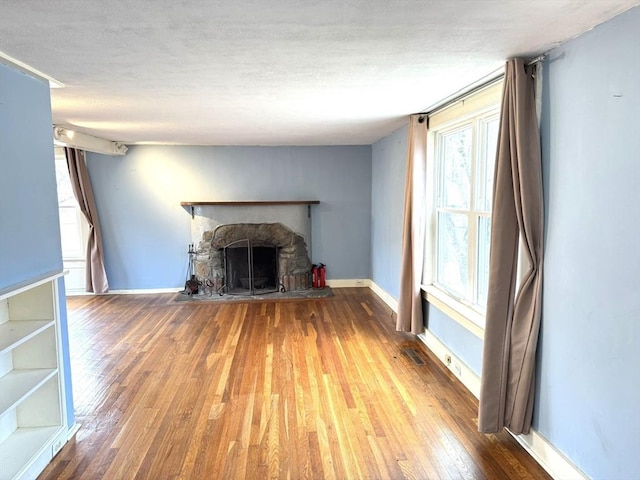 unfurnished living room with a fireplace, baseboards, hardwood / wood-style floors, and a textured ceiling