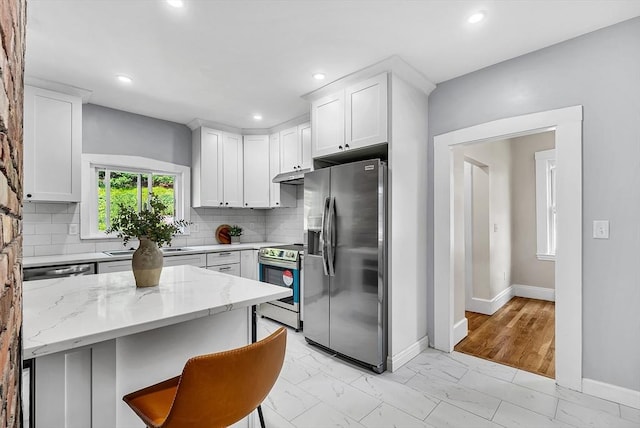 30 Forest Park Rd, Woburn, MA 01801 - kitchen with appliances with stainless steel finishes, under cabinet range hood, light marble finish flooring, light stone countertops, and tasteful backsplash