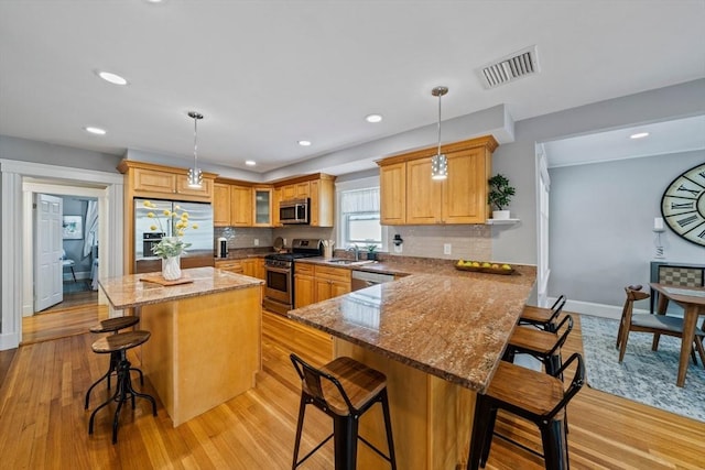 324 Mount Auburn St Unit 2, Watertown, MA 02472 - kitchen featuring appliances with stainless steel finishes, a breakfast bar, tasteful backsplash, light wood-style flooring, and recessed lighting